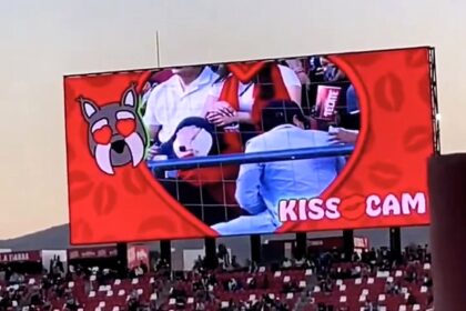 Couple caught on kiss cam at Mexican soccer match desperately hide faces as crowd jeers. Man turns 180 degrees away. Viral moment compared to Coldplay cheating scandal.