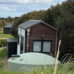 Woman saves £70,000 on bills living in 194 sq ft tiny home for 9 years in New Zealand. Features composting toilet and million-dollar view. Says she made right choice.