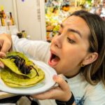 An influencer was left with prickly hairs stuck in her mouth after eating a tarantula taco at a Mexican market - saying the spider surprisingly tasted like pork scratchings.