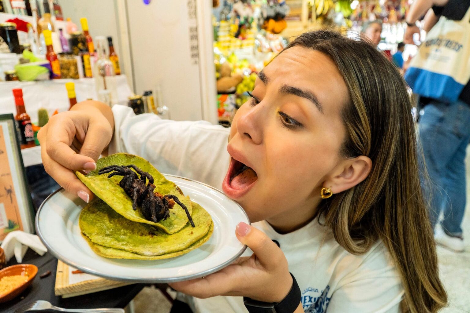An influencer was left with prickly hairs stuck in her mouth after eating a tarantula taco at a Mexican market - saying the spider surprisingly tasted like pork scratchings.