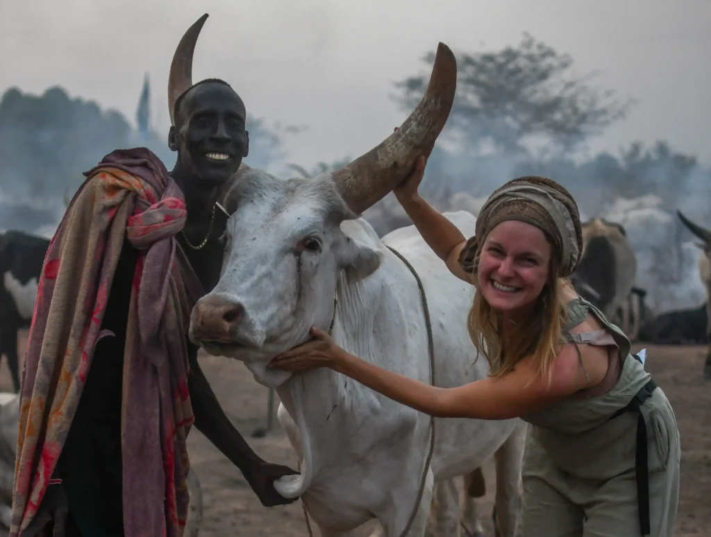 A travel influencer shocked fans after washing her hair in cow urine as part of the Mundari tribe spa experience in South Sudan - squatting under a cow as part of the ritual.