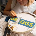 Greggs has unveiled a Bayeux Tapestry-inspired Ta-Pastry with 5.5 million stitches tracing the sausage roll's near-century history, on display at London's Design Museum.