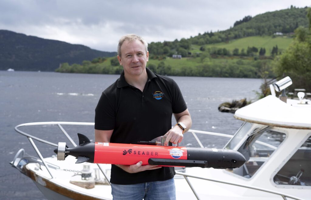 Hi-tech underwater robot searching Loch Ness successfully tracks down iconic Nessie film prop hidden beneath murky depths as monster hunters descend from around the world.