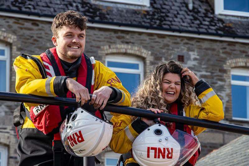 RNLI lifeboat crew surprised newlywed colleagues with a guard of honour made from gig boat oars and the charity's iconic yellow wellies after their Cornwall clifftop wedding.