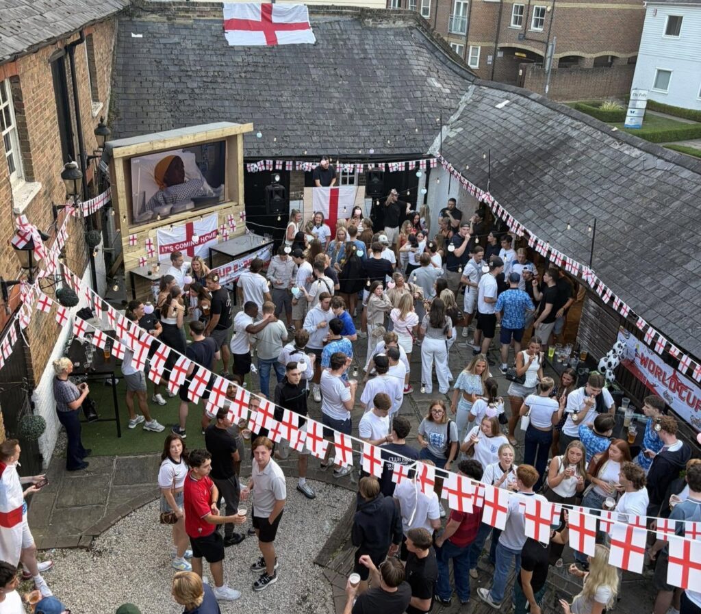 Pints fly as England fans erupt in a packed pub beer garden, celebrating a dramatic 3-2 World Cup win over Mexico that sends the Three Lions through to face Norway.