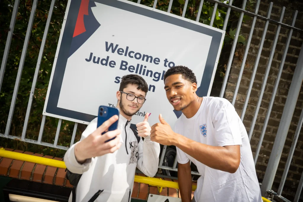 Jude Bellingham lookalike sparks chaos at a train station renamed in the star's honour, with fans mobbing him for selfies ahead of England's World Cup semi-final.
