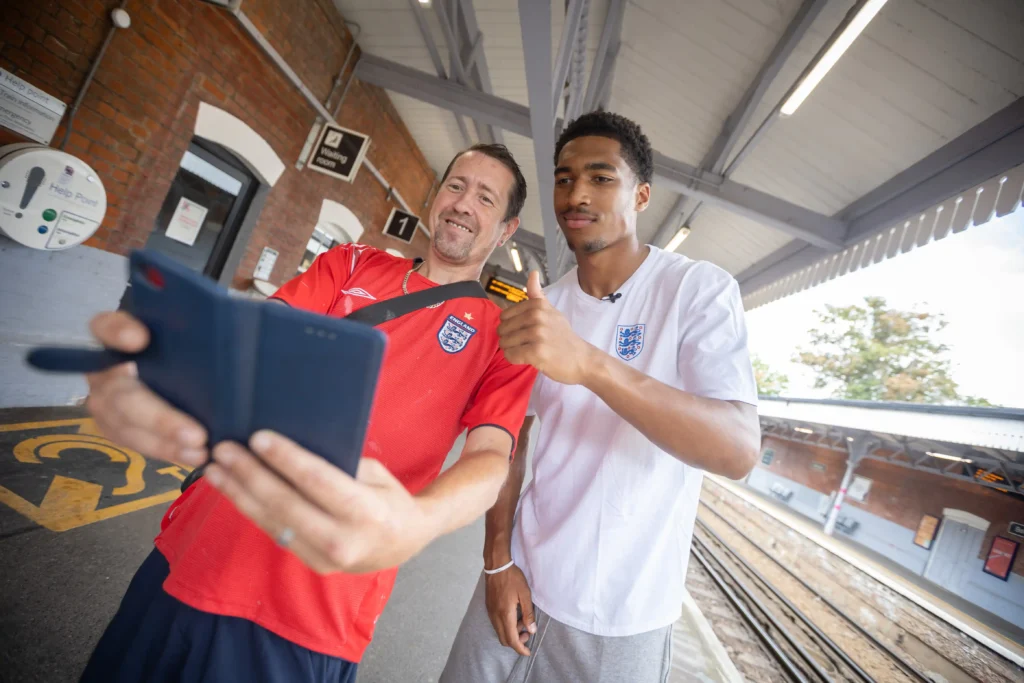 Jude Bellingham lookalike sparks chaos at a train station renamed in the star's honour, with fans mobbing him for selfies ahead of England's World Cup semi-final.