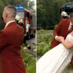 Bride and groom carry on with their wedding photos in a storm - dancing in the rain as firefighters clear a fallen tree from the road behind them.
