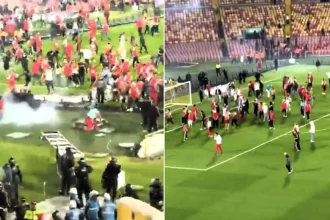 A football match was suspended for nearly an hour after rival fans invaded the pitch and brawled with sticks and chairs in front of thousands of spectators.
