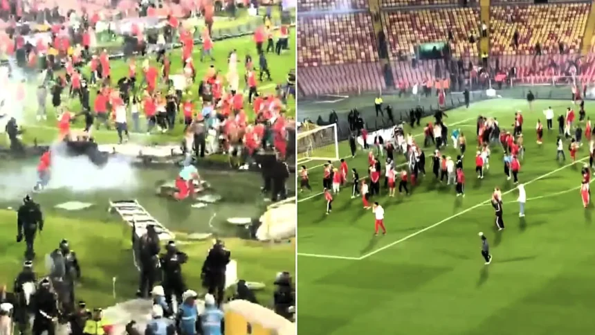 A football match was suspended for nearly an hour after rival fans invaded the pitch and brawled with sticks and chairs in front of thousands of spectators.