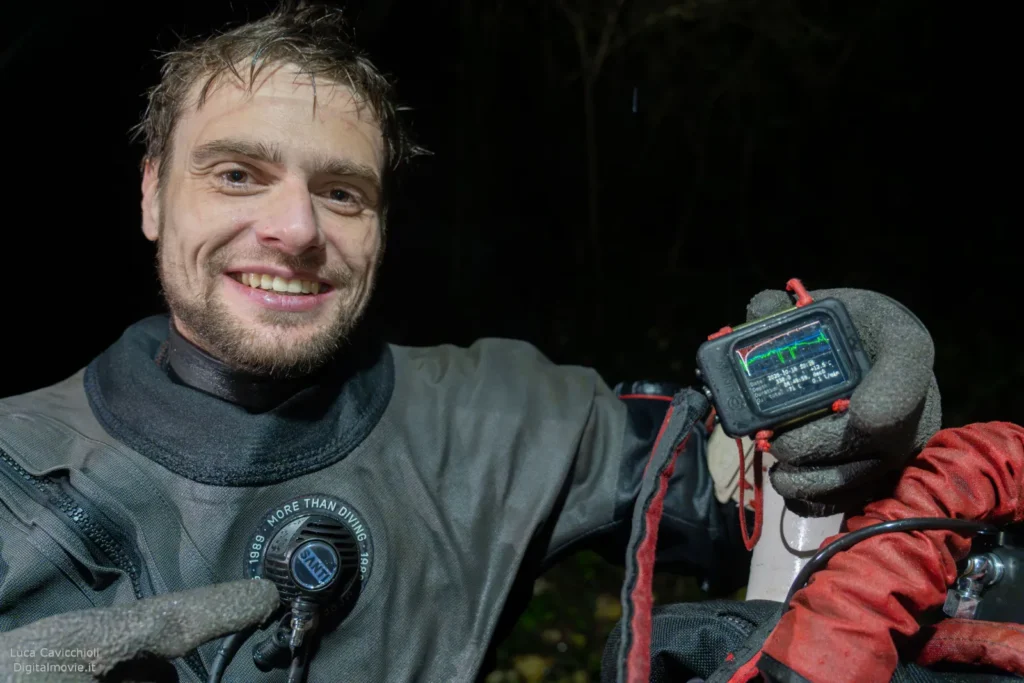 Bart Pitala smiling above water holding dive computer display.