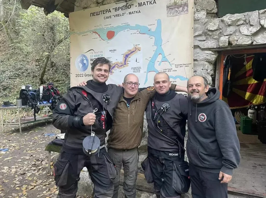 Bart Pitala with three team members at cave entrance by map display.