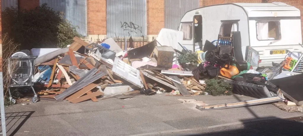 A caravan and mounds of fly-tipped rubbish have sparked fury after spilling onto a quiet Gloucester street near an abandoned school. Residents demand action.