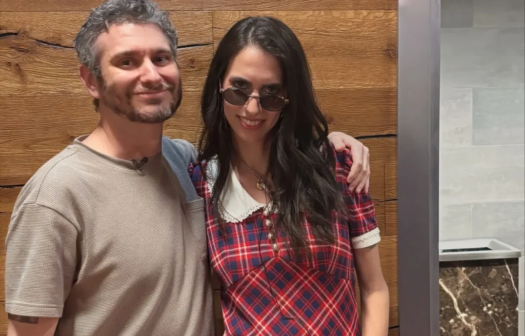 Ethan and Hila Klein standing together indoors in casual clothing.