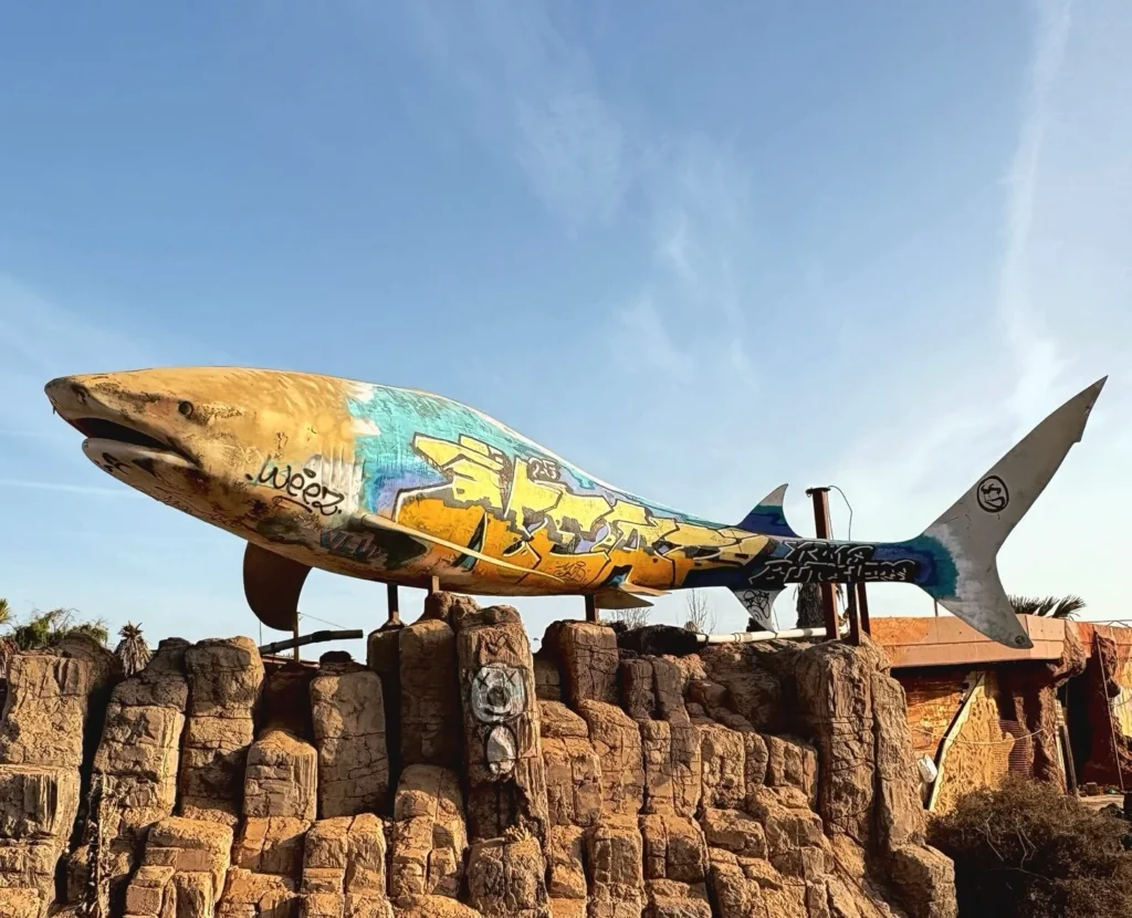 Eerie pictures reveal a former Spanish holiday attraction where sharks once swam, but now a giant graffiti-covered predator overlooks the decaying complex.