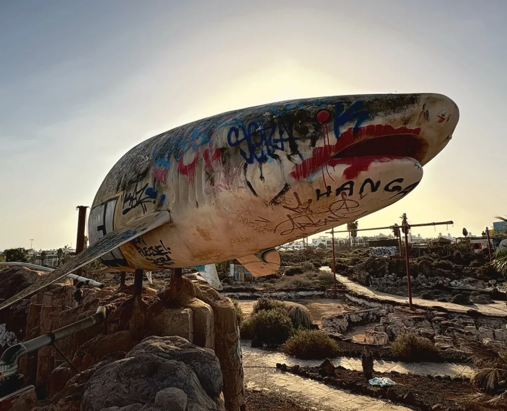 Eerie pictures reveal a former Spanish holiday attraction where sharks once swam, but now a giant graffiti-covered predator overlooks the decaying complex.
